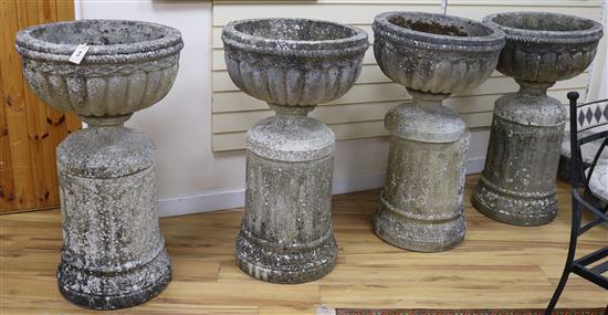 A set of four large cup shaped garden urns on fluted plinths (one a.f.)